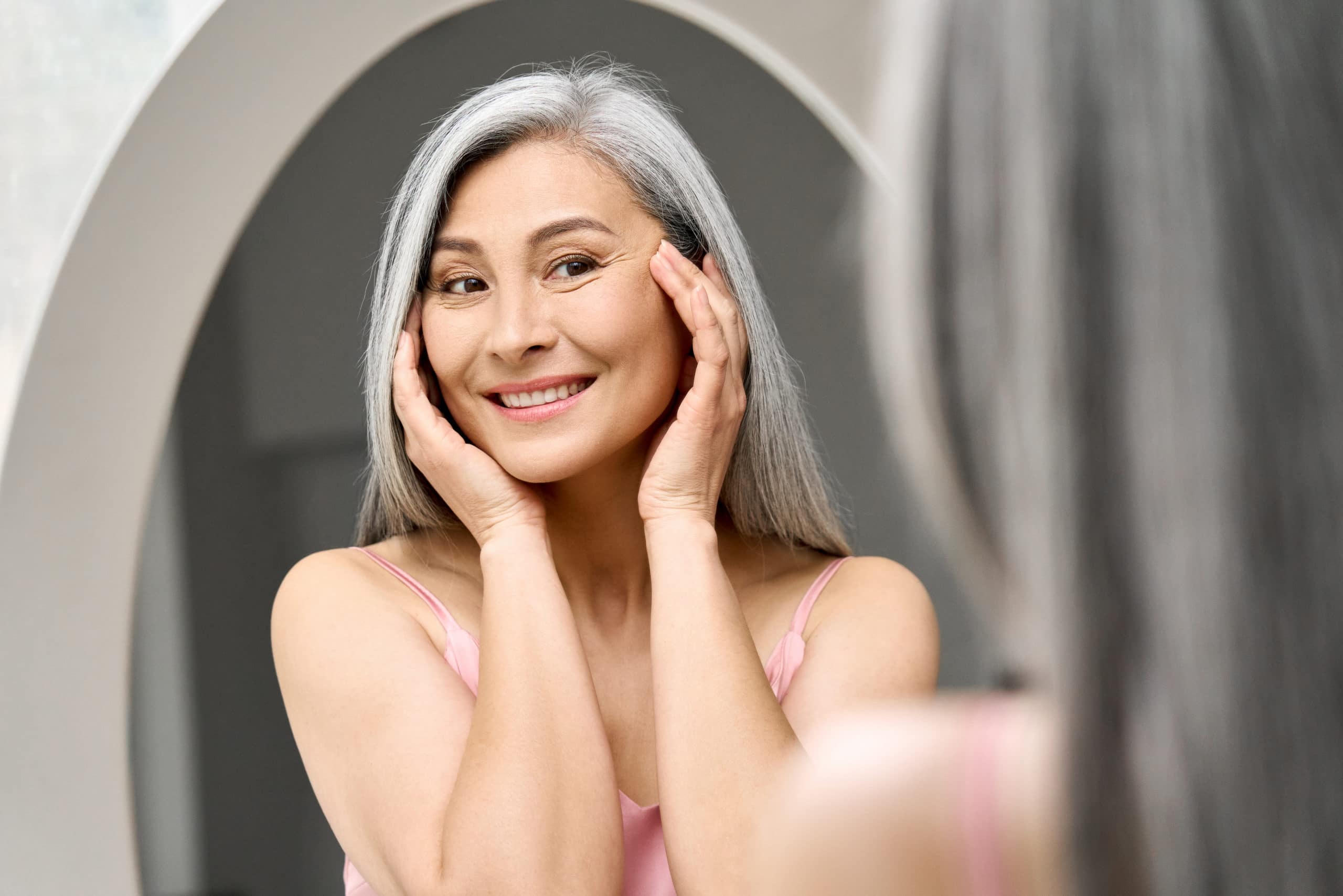 Happy-mid-aged-Asian-woman-looking-at-mirror