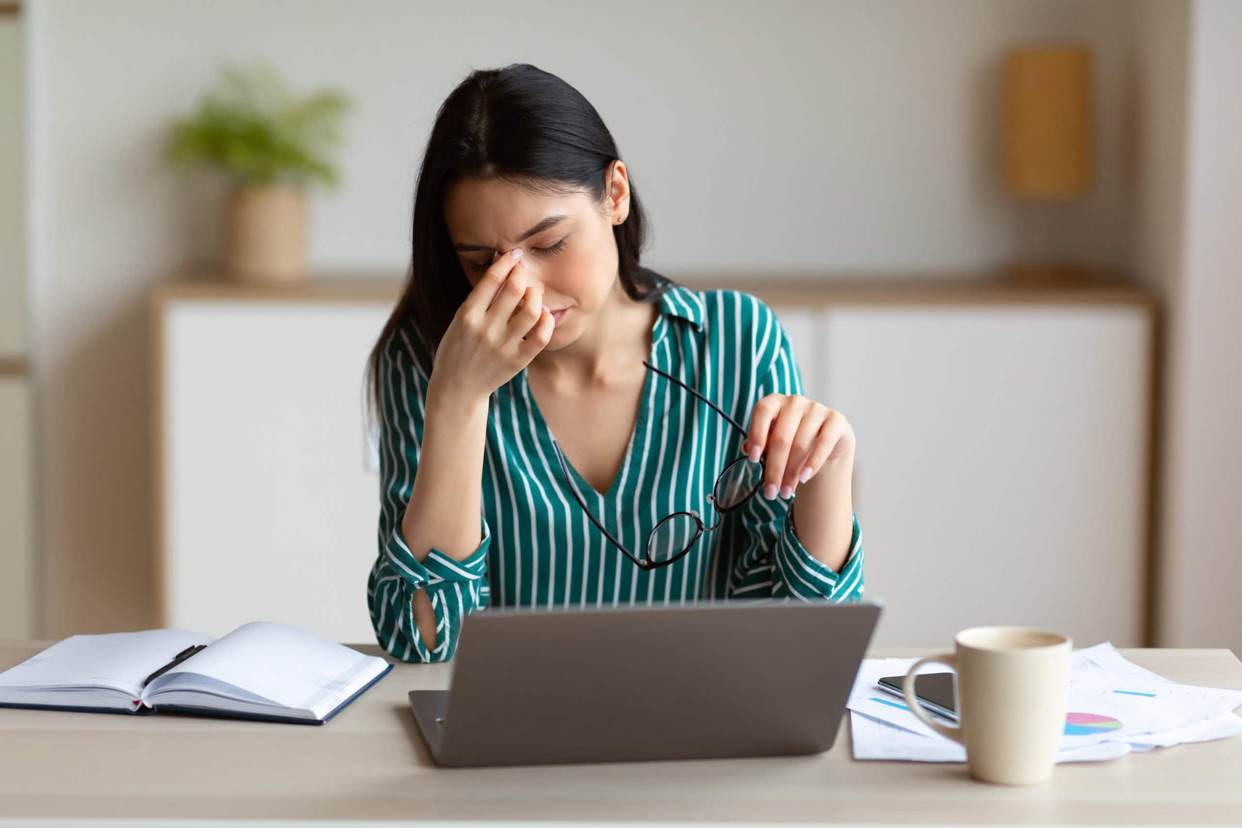 Woman Having Eyes Fatigue Massaging Nosebridge Working In Office