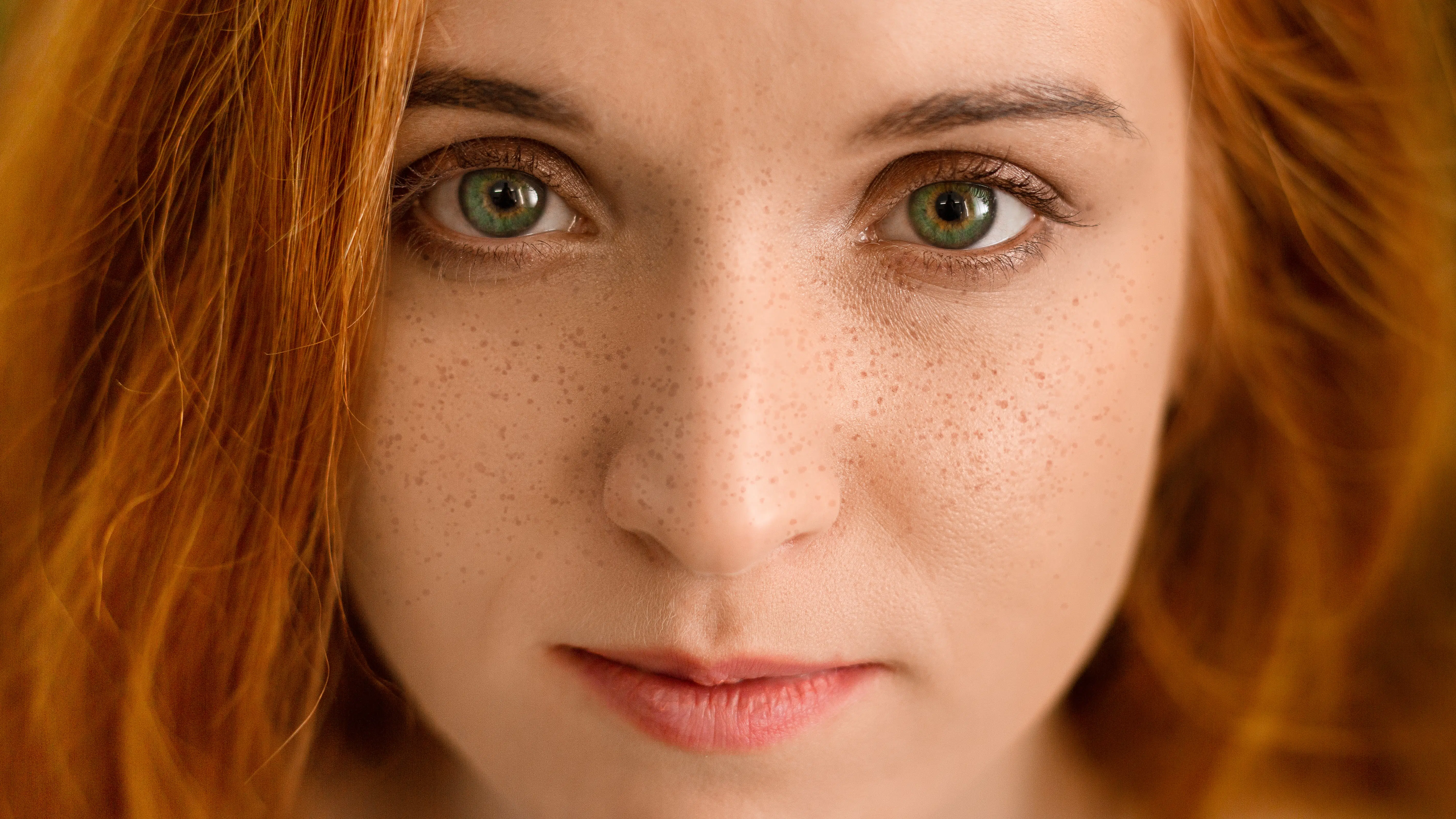 Young redhead woman with freckles looking at camera